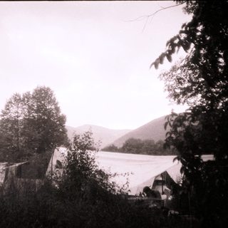 Rural mountain campsite with tents and cabins.