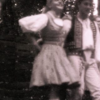 Traditional folk dancers in forest setting.