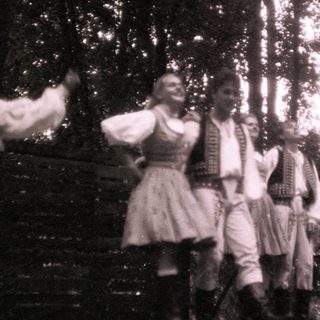 Traditional folk dancers in forest setting.
