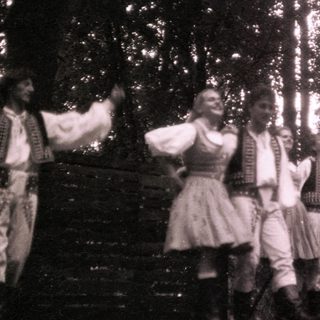 Traditional folk dancers in forest setting.