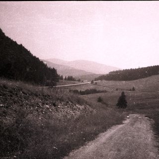Rural mountain road winding through forested valley.