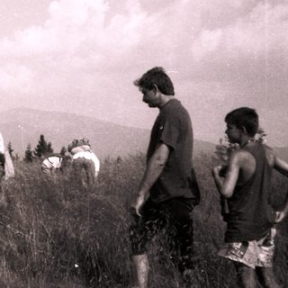 Group hiking on grassy hilltop.