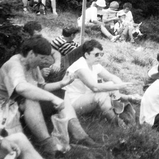 Group of people relaxing outdoors near forest trail sign.