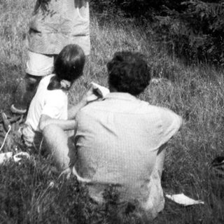 Family hiking with picnic basket in forested area.
