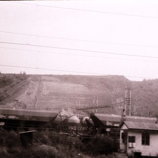 Railroad tracks with overturned train cars and damaged landscape.
