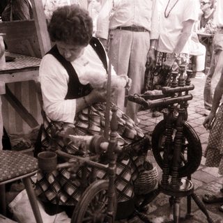 Woman spinning yarn on traditional spinning wheel.