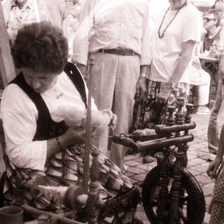 Woman spinning yarn on traditional spinning wheel.