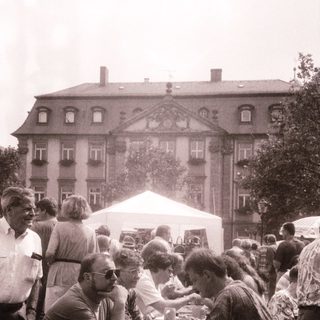 Outdoor gathering with people seated at tables.