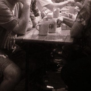 Outdoor gathering with people seated at tables.