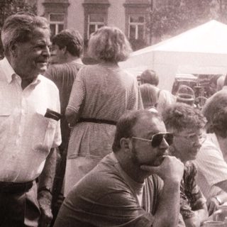 Outdoor gathering with people seated at tables.