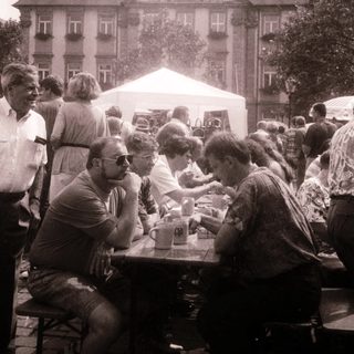 Outdoor gathering with people seated at tables.