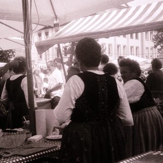 Vintage outdoor market scene with women serving food.