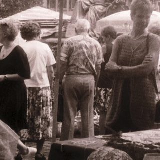 Outdoor market scene with food stalls and people.