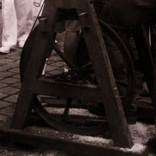 People operating traditional spinning wheel outdoors at fair.