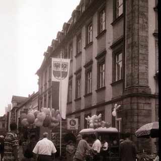 Street celebration with balloons, bicycles, and people.