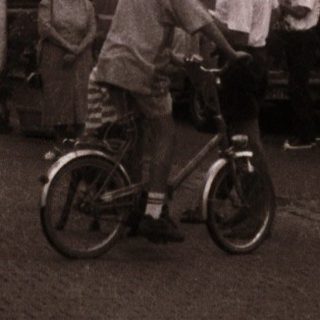 Street celebration with balloons, bicycles, and people.