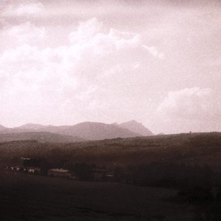 Rural landscape with distant hills and cloudy sky.