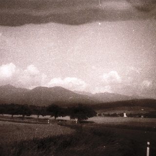 Rural landscape with distant mountains and cloudy sky.