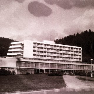 Mid-century modern hotel building in forested area.