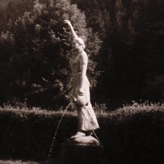 Statue of a robed figure in outdoor setting.