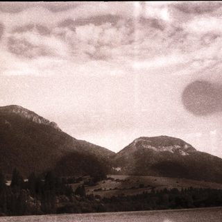 Mountainous landscape with lake and cloudy sky.