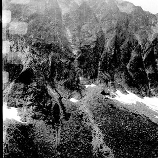 Steep rocky mountain slope with snow patches.