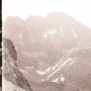 Mountainous terrain with steep cliffs and snow patches.