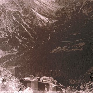 Aerial view of mountainous terrain with dam and reservoir.