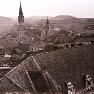 Historic town with prominent church spires and sloped rooftops.