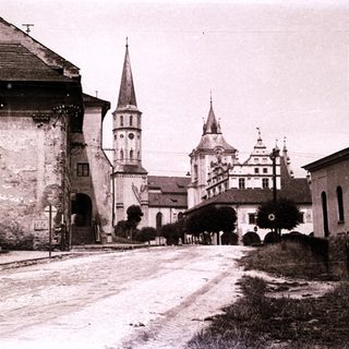 Historic town scene with church towers and castle ruins.