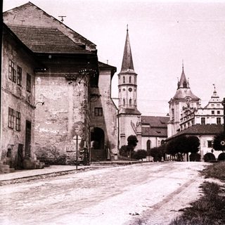 Historic town scene with church towers and castle ruins.