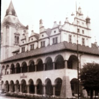 Historic building with arched colonnade and steep gabled roofs.