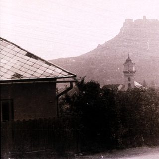 Historic town with castle on hill, foggy street scene.