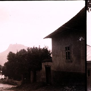 Rural village scene with mountain fortress in background.