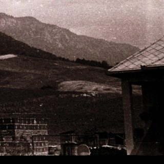Rural mountain landscape with old buildings and farmland.