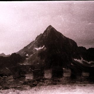 Mountain peak with snow and rocky foreground.