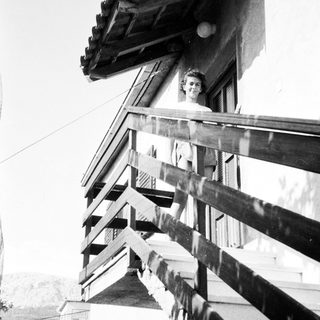 Woman leaning from wooden balcony.