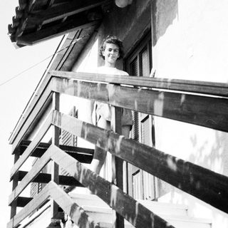Woman leaning from wooden balcony.