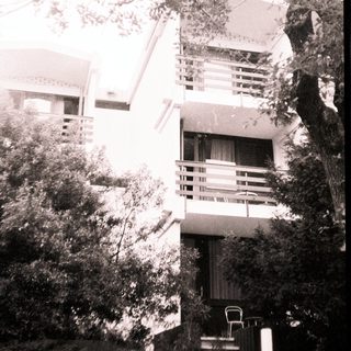 Modernist building with elevated terrace and greenery.
