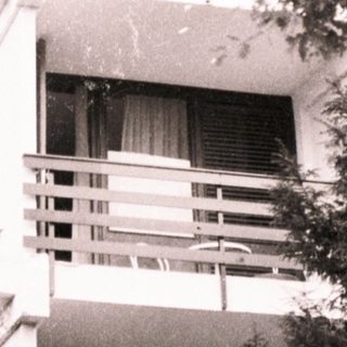 Modernist building with elevated terrace and greenery.