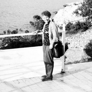 A person standing by a seaside cliff overlooking water.