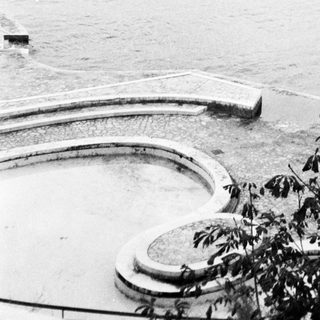 Coastal area with circular pool, pier, and lighthouse structure.