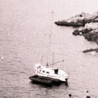 Coastal harbor with rocky cliffs and small boat.