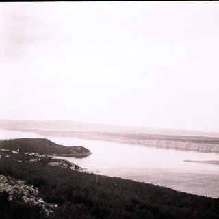 Coastal landscape with rocky hills and distant shoreline.