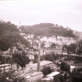 Historic hillside town with industrial chimney.