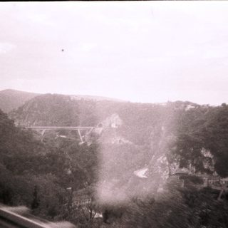 Rustic bridge spanning valley with misty hills.