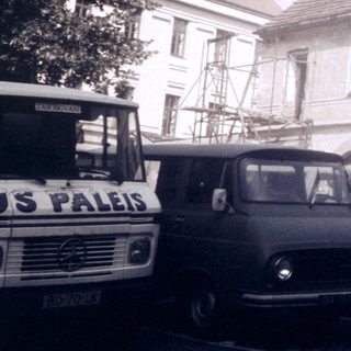 Vintage European street scene with parked vehicles and old buildings.
