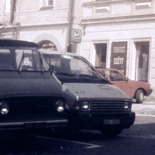 Vintage European street scene with parked vehicles and old buildings.