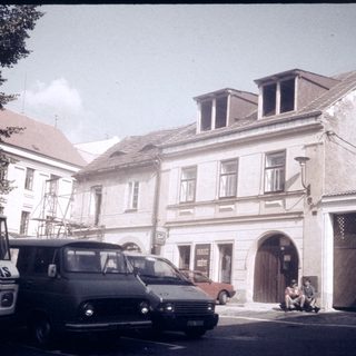 Vintage European street scene with parked vehicles and old buildings.
