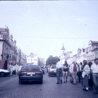 Busy European street scene with pedestrians and cars.
